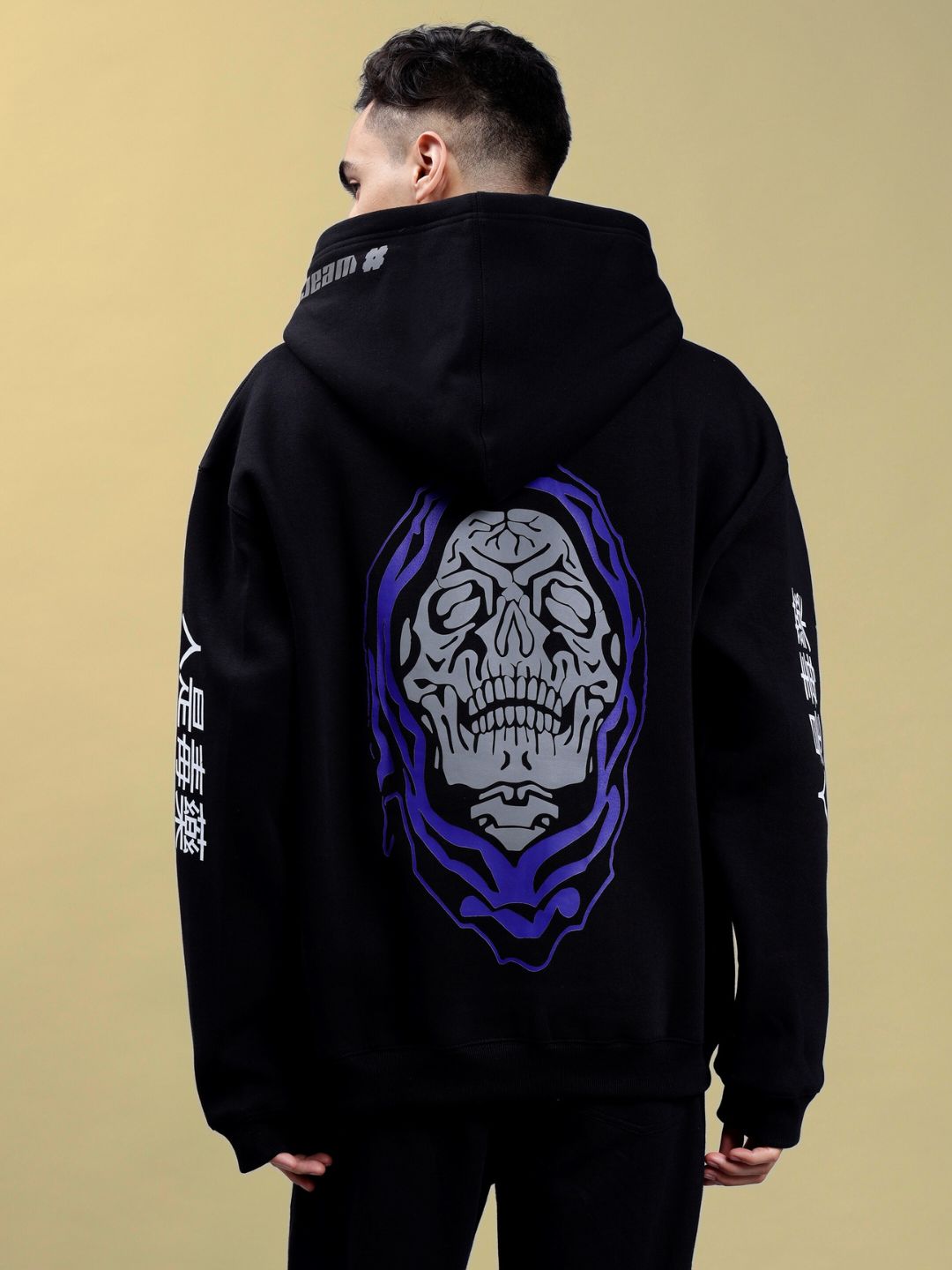 POISON SKULL REFLECTOR OVERSIZE HOODIE BLACK with skull design on the back worn by person against a beige background