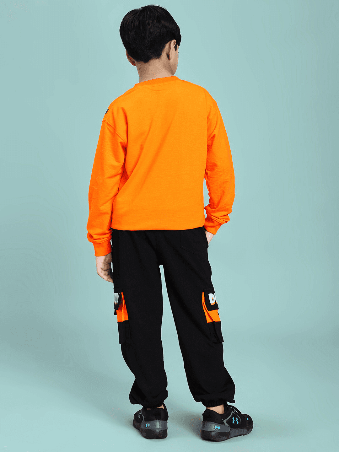 Boy wearing TIGON KIDS CO-ORD SET FOR BOYS AND GIRLS ORANGE BLACK, showing back view with vibrant orange top and black pants.