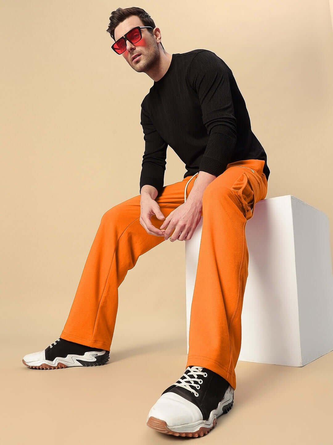 Model wearing orange relaxed fit joggers with black top and sneakers, showcasing JESS 5 POCKET style by DUDS.