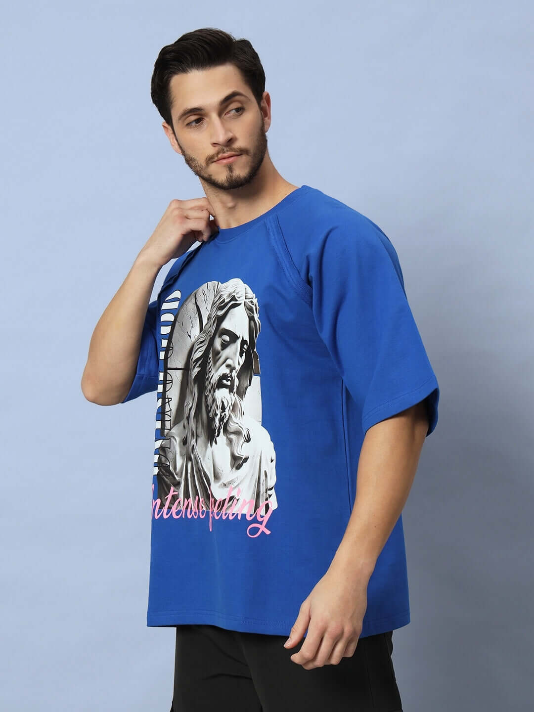 Man wearing REGLAN DYING GOD OVER-SIZED T-SHIRT ROYAL BLUE standing against light background.