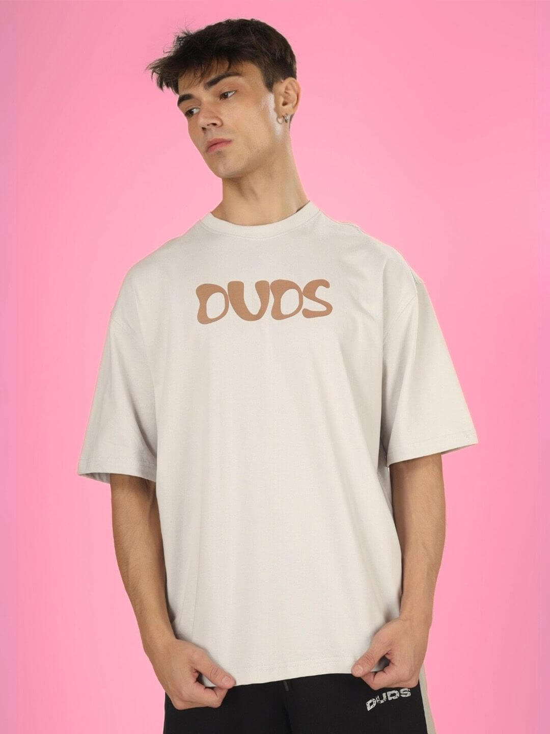 Model wearing HIGH AS FUCK OVER-SIZED T-SHIRT BUTTER CREAM in front of pink background.