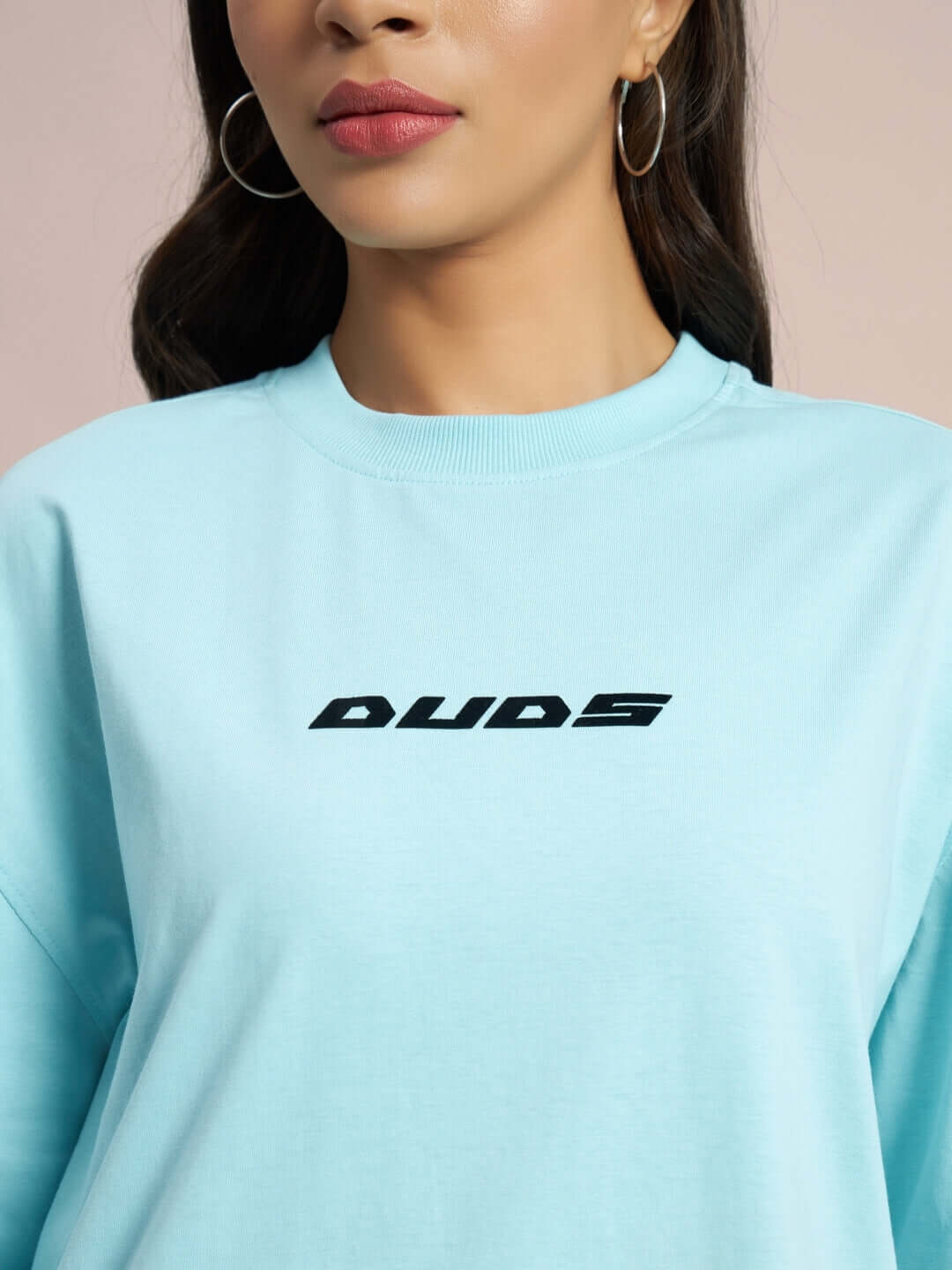 Model wearing sky blue over-sized t-shirt with 'DUDS' logo, ideal for customizable fit options.