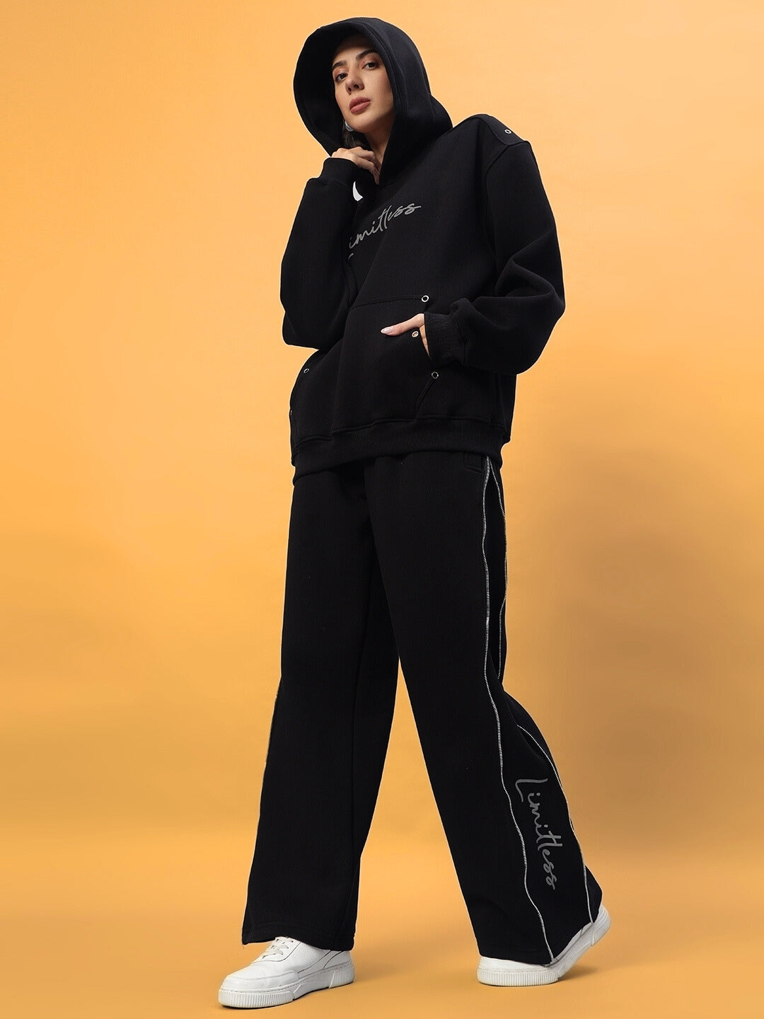 Model wearing black Women's Limitless Fleece Reflector Jogger with hoodie and reflective details, showcasing modern and cozy style.