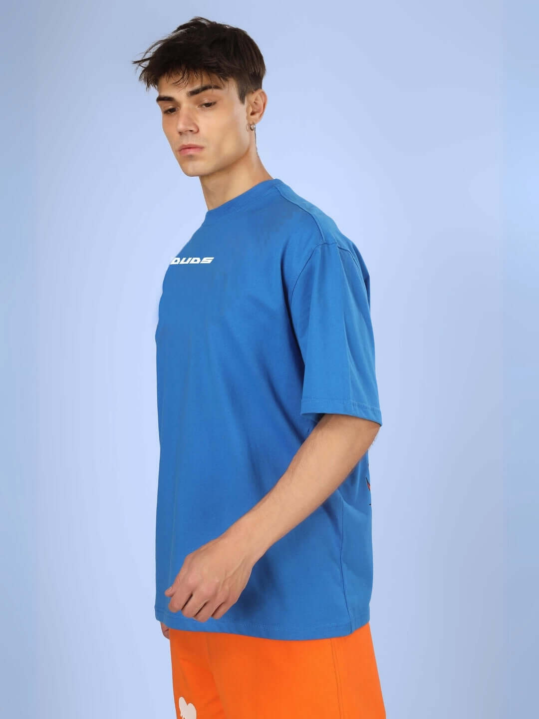 Side view of a model wearing DUDS VAN OVER-SIZED T-SHIRT ROYAL BLUE with orange shorts.