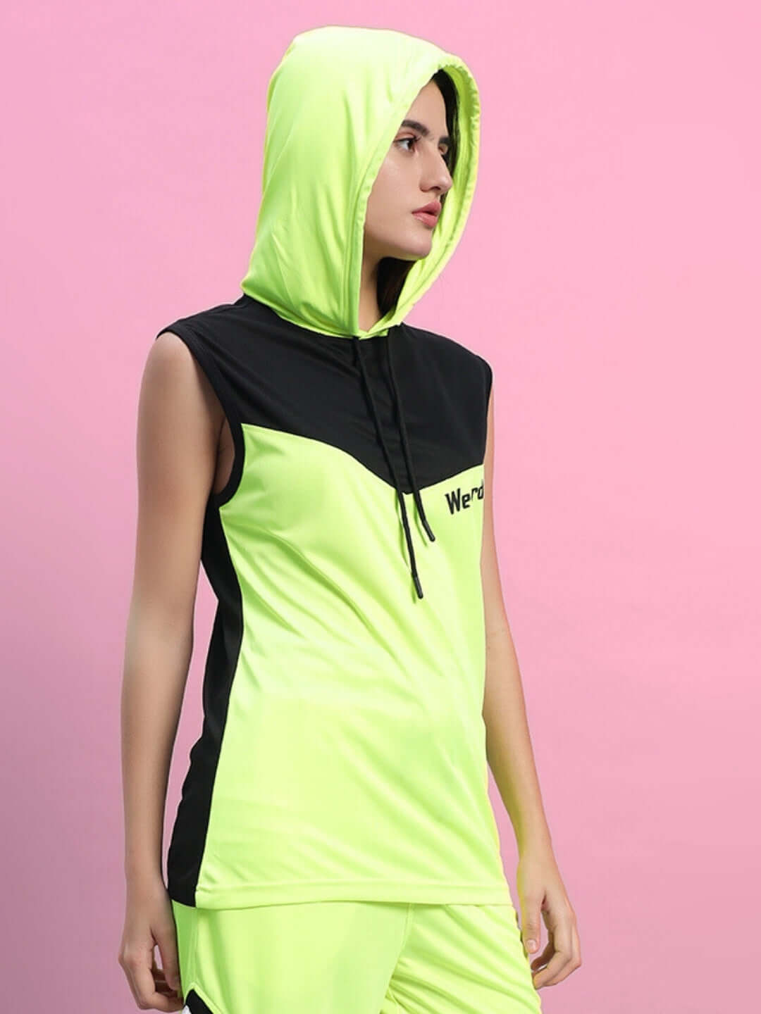 Woman wearing neon green Franky gym t-shirt with hoodie against pink backdrop.
