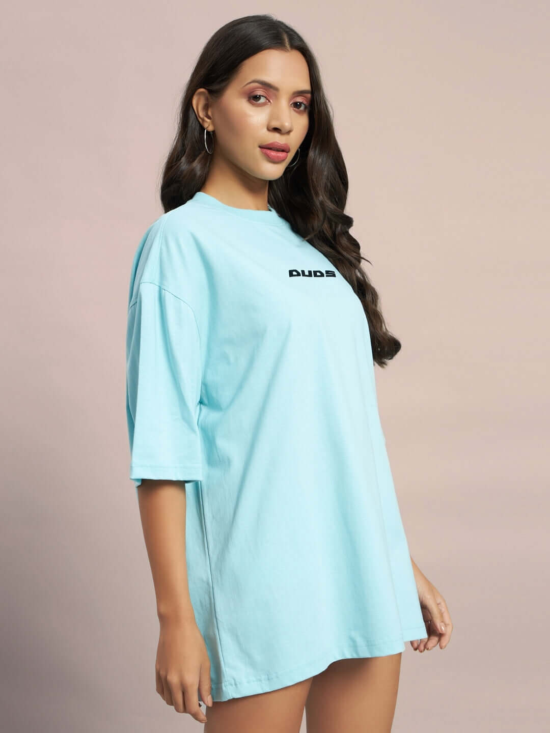 Model wearing sky blue oversized t-shirt, women's ethereal creatures collection by DUDS, side view.