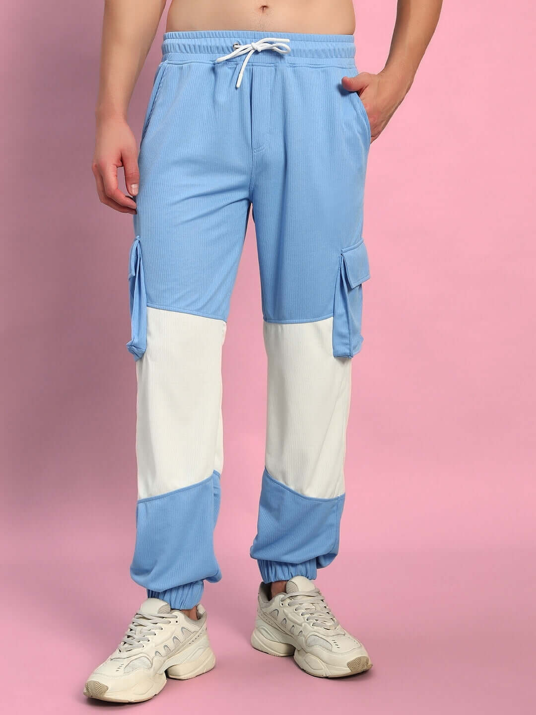 Person wearing Radiant Relaxed Fit Joggers in white and sky blue, tailored by DUDS, standing against a pink background.