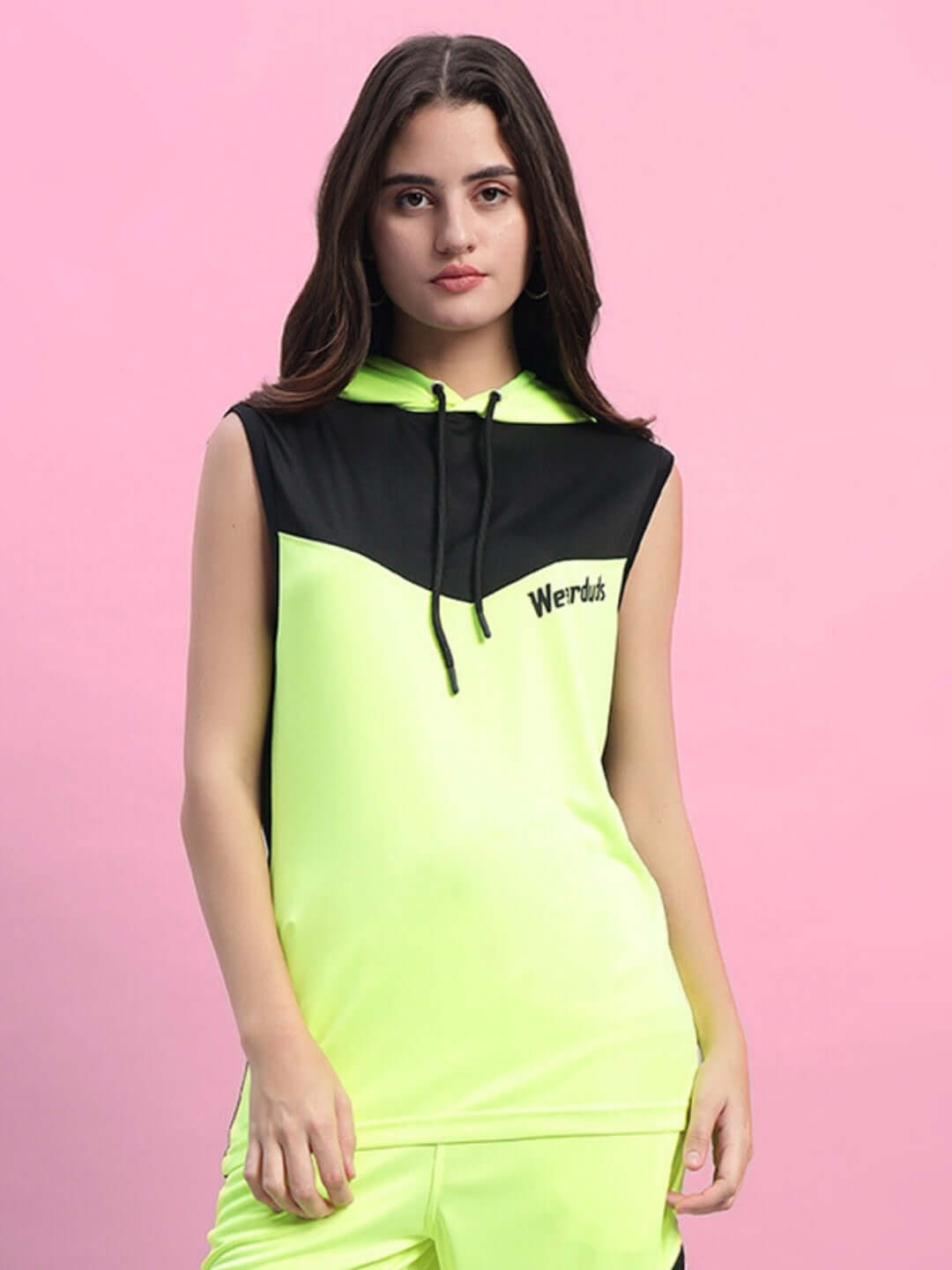 Woman wearing Franky Gym T-shirt in neon green, featuring a customizable fit option from DUDS, against a pink background.