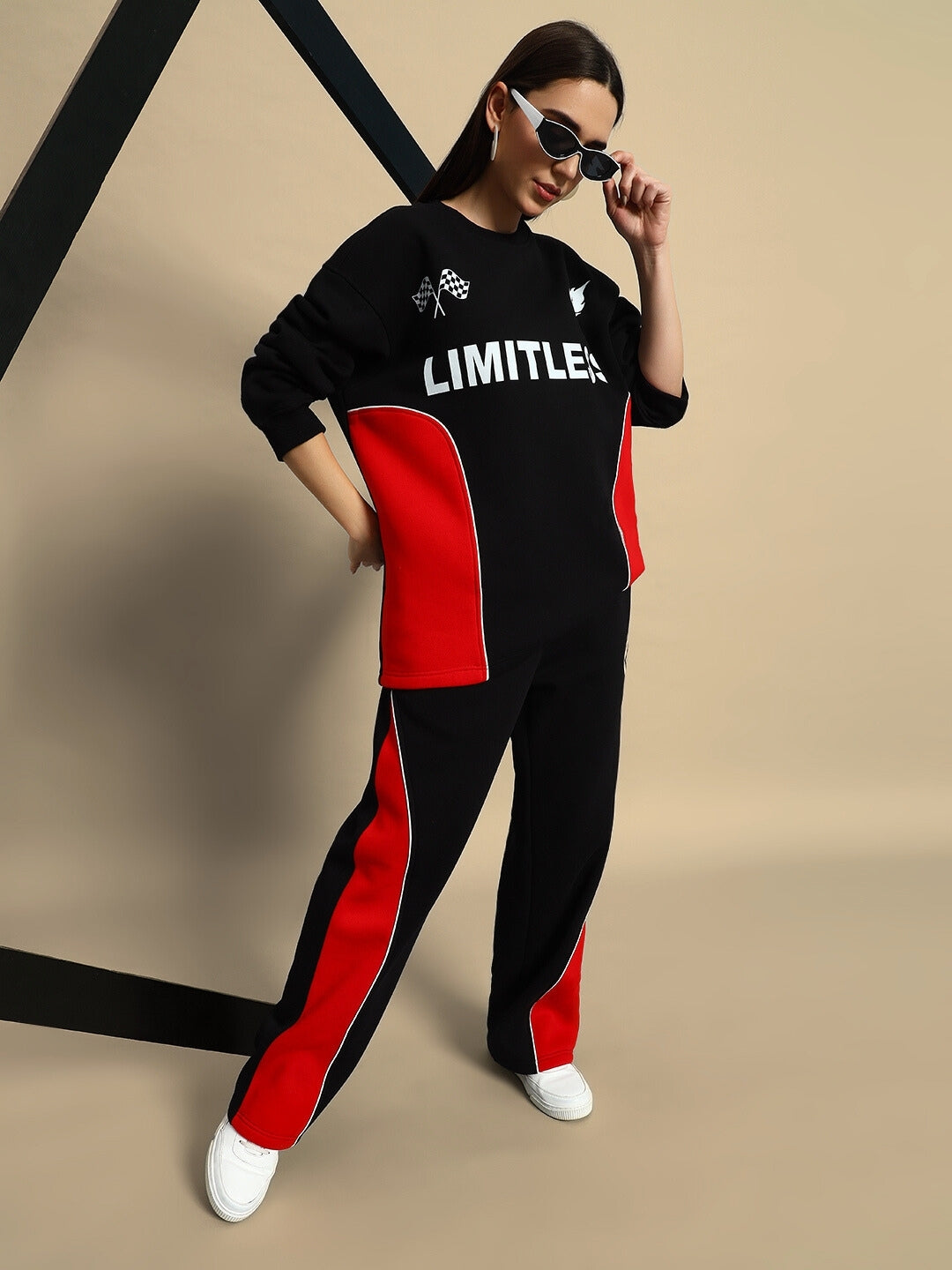Woman wearing black and red colorblock co-ord set with the word 'Limitless' on the top, styled with sunglasses and white sneakers.