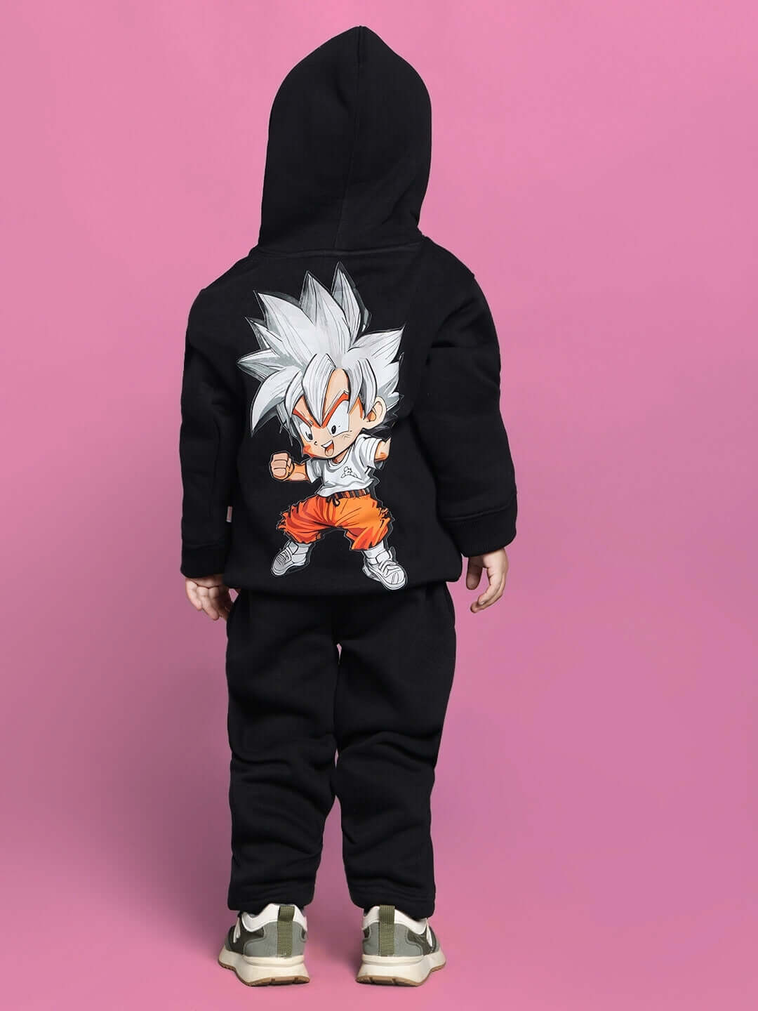 Child wearing black Gohan co-ord set with cartoon character on back, suitable for boys and girls, against pink background.