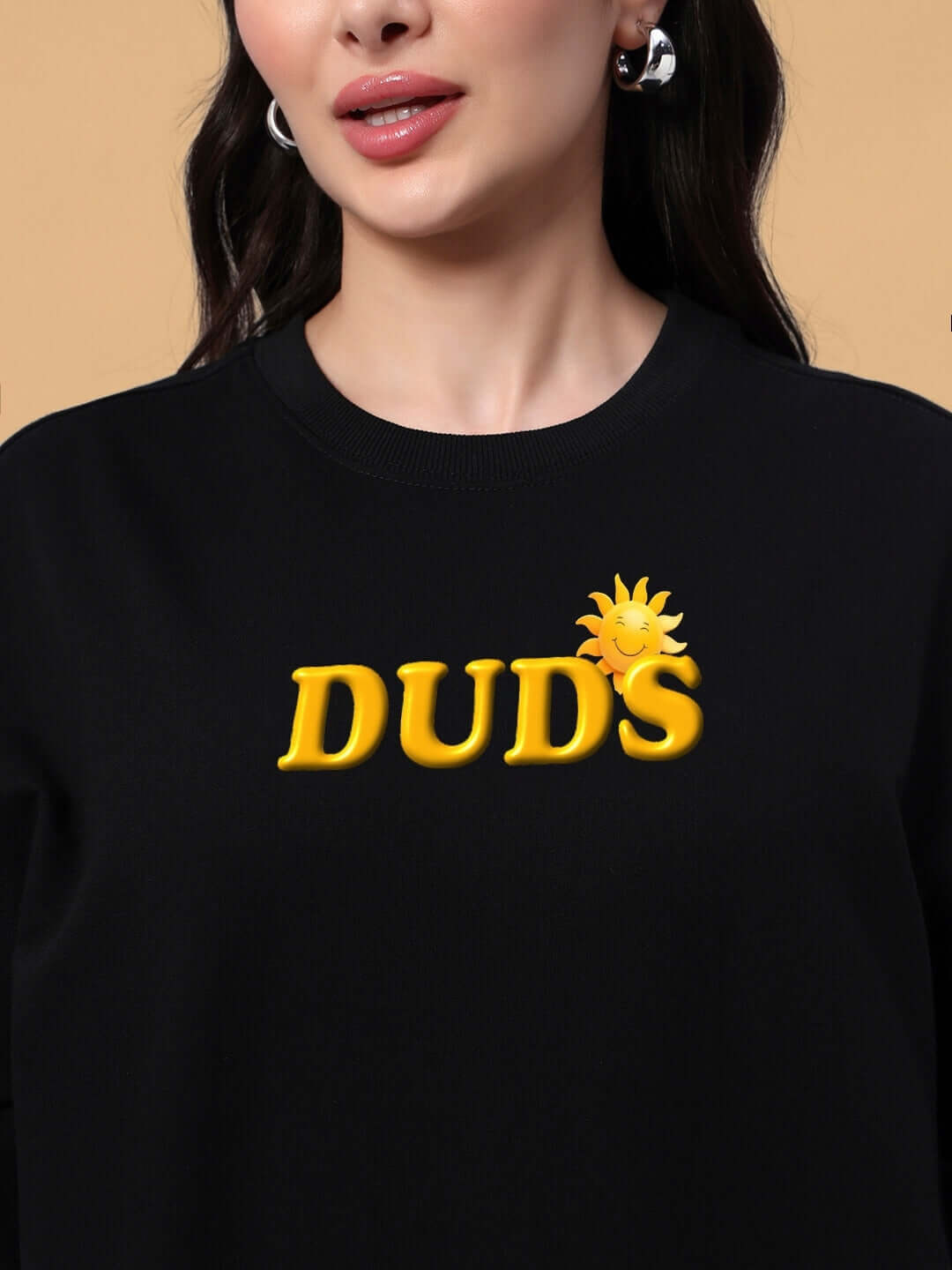 Close-up of a woman wearing a black oversized t-shirt with yellow 'DUDS' text and a sun graphic, highlighting the trendy summer design.