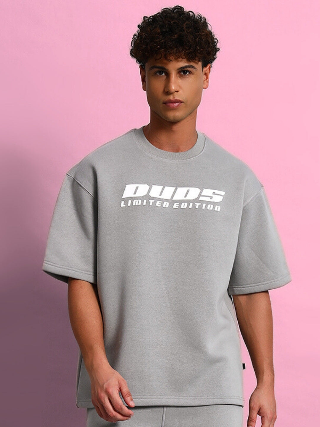 Grey oversized Skoda fleece t-shirt worn by model against pink background, featuring 'Dudes Limited Edition' print on the chest.