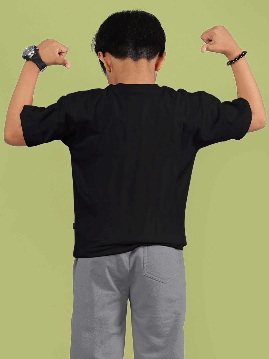 Child wearing black SNOOPY RIMIX T-shirt, showing back view, flexing arms in stylish pose.