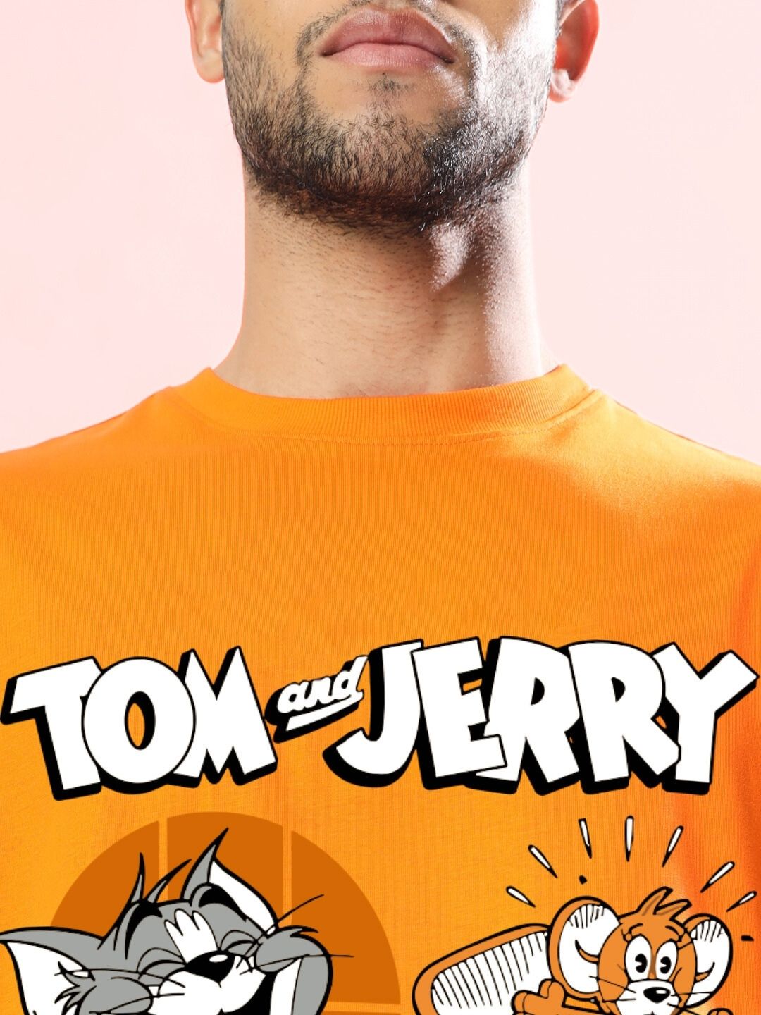 Close-up of a TOM AND JERRY TOAST OVERSIZED T-SHIRT ORANGE on a man, featuring classic cartoon characters.