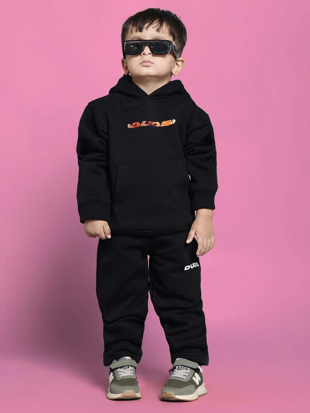 Child wearing GOHAN black co-ord set for boys and girls, featuring hoodie and pants, against pink background.