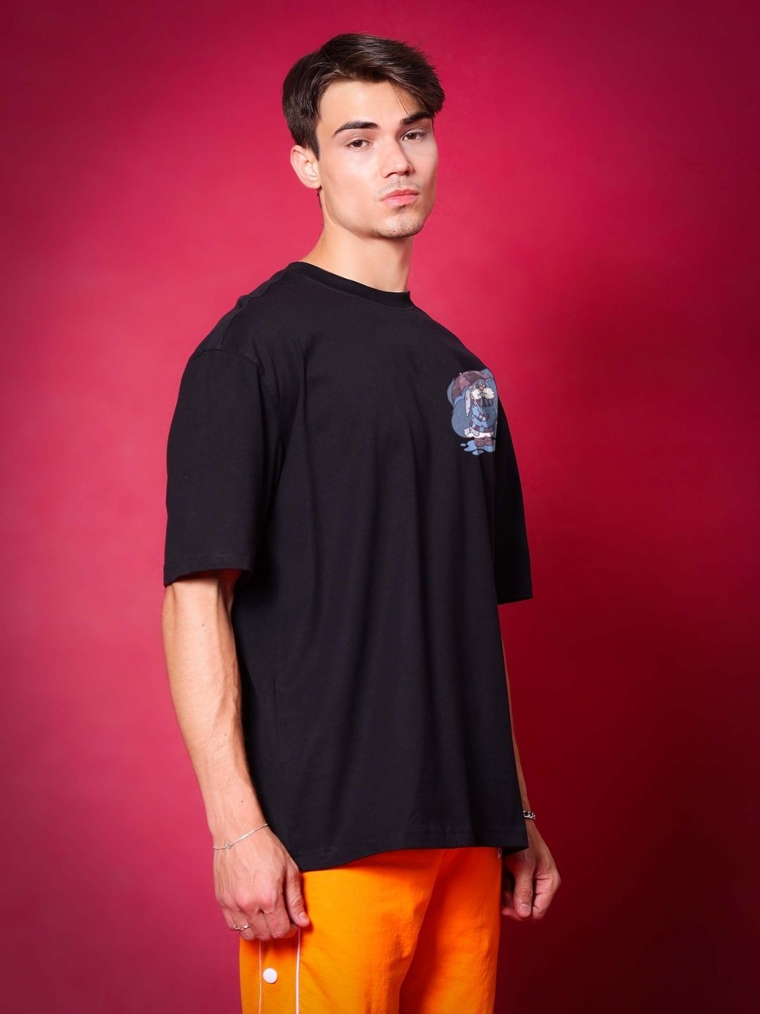 Man wearing BLUE LAPIN OVER-SIZED T-SHIRT BLACK with a red background. Premium cotton French terry fabric blend displayed.