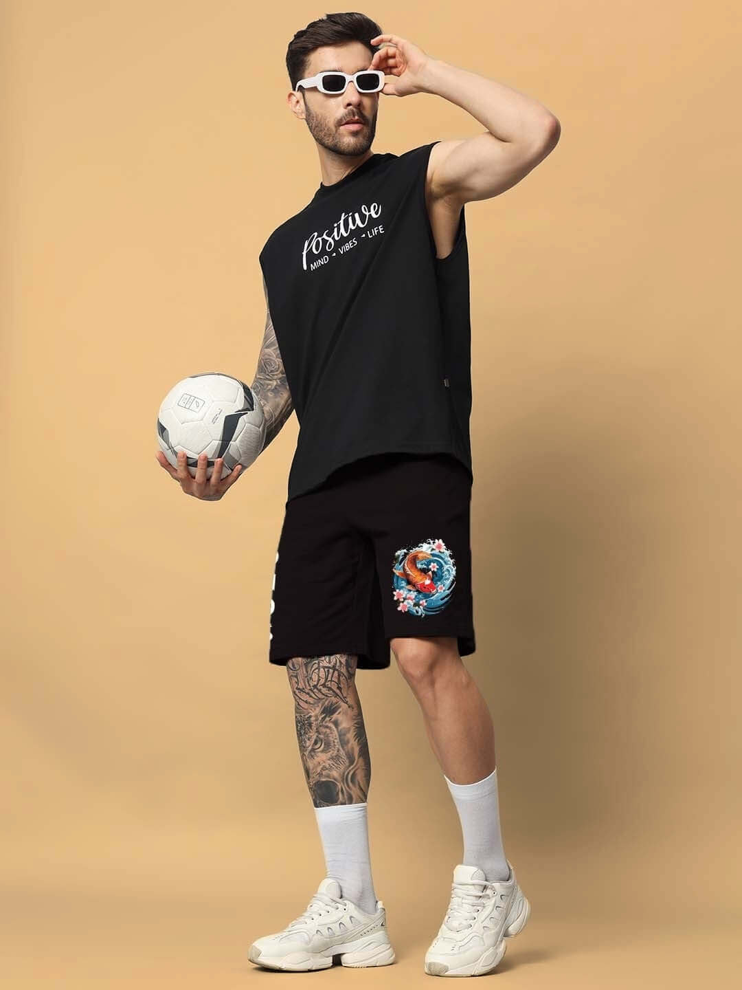 Man wearing Majestic Fish regular fit shorts in black, holding a soccer ball, showcasing sporty casual style.