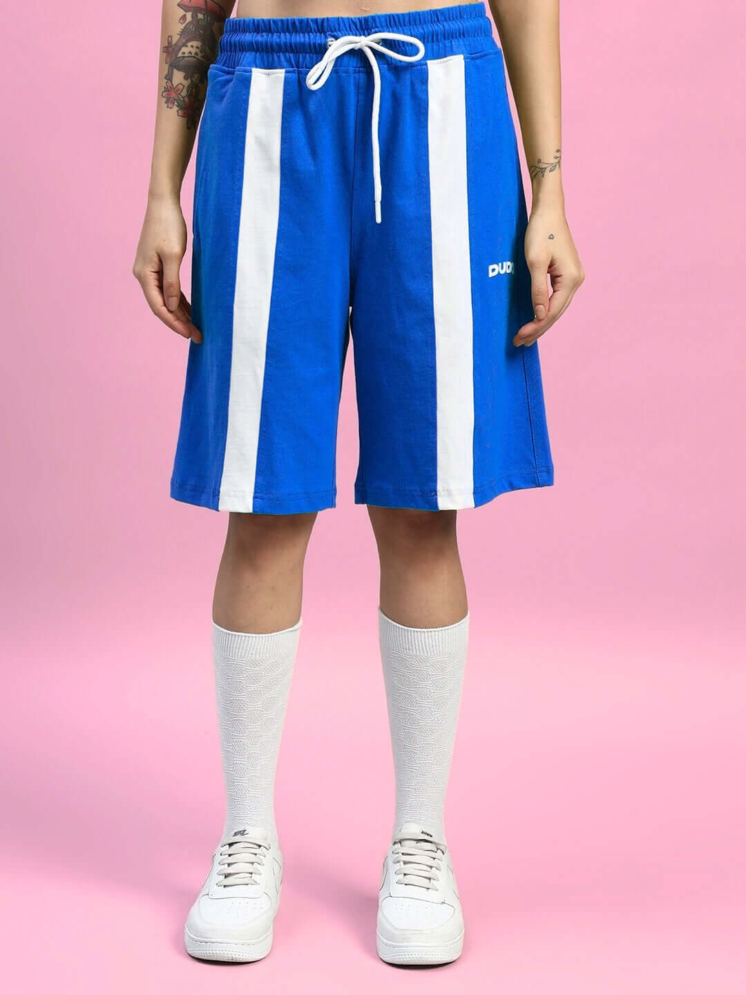 Women's blue wideline shorts with white stripes, regular fit, shown with white socks and sneakers.