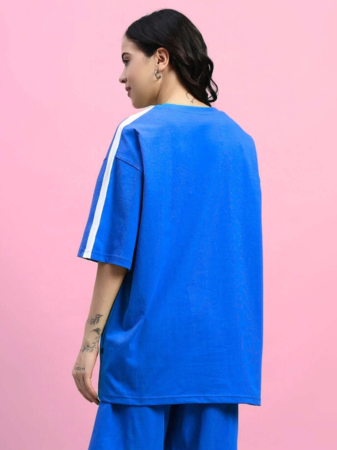 Blue women's oversized T-shirt in premium cotton fabric, featuring white stripe detail, designed by Color By Colours. Side profile view.