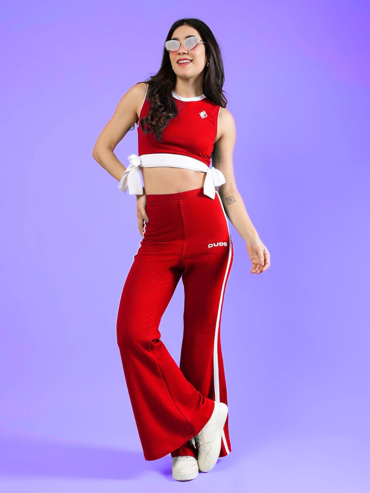 WOMENS FITTONIA COOL WIDE FLARE JOGGERS RED worn by a woman with sunglasses against a purple background.