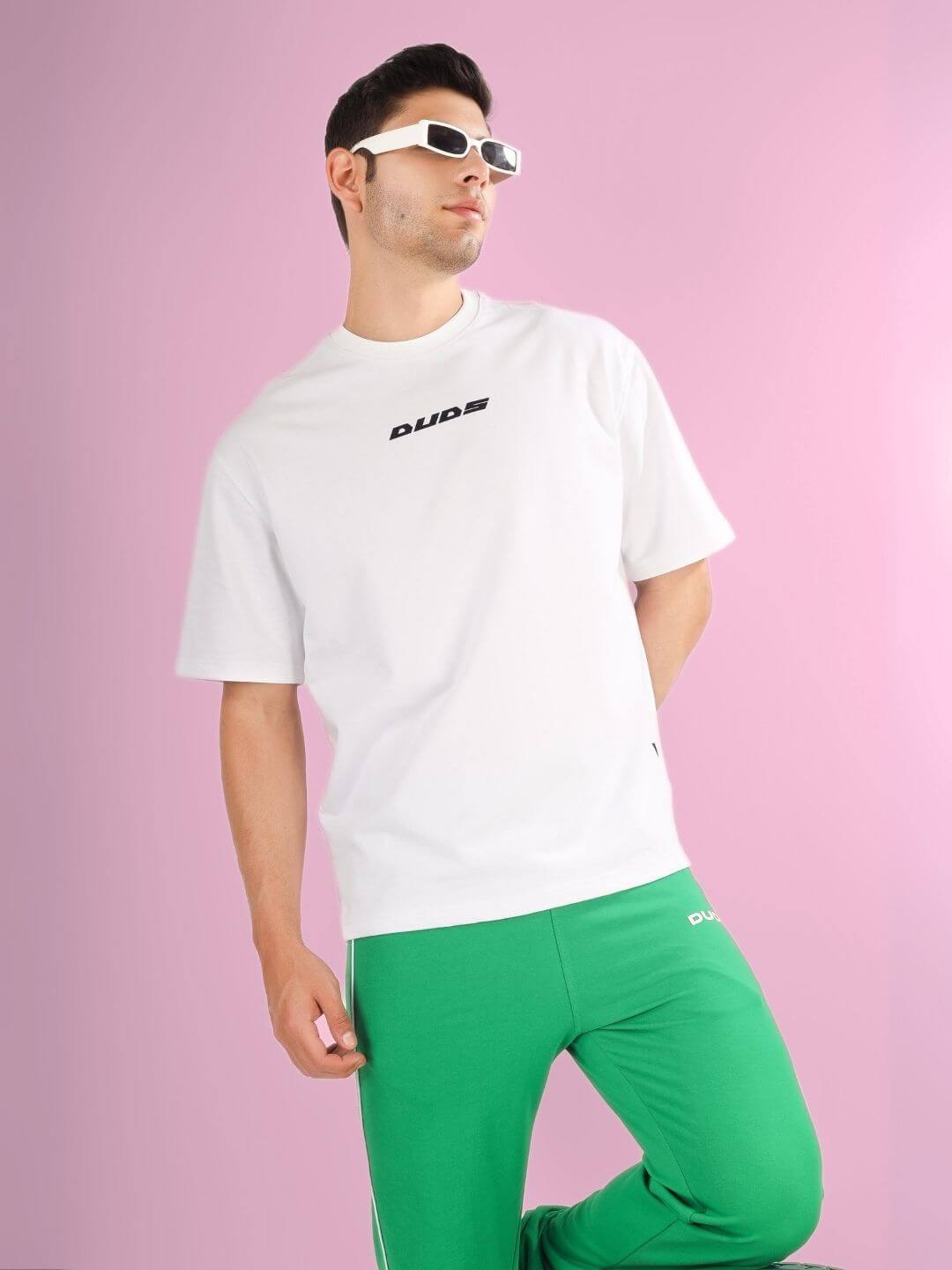 Model wearing DONT STOP OVER-SIZED T-SHIRT WHITE made from premium cotton and elastane fabric, styled with green pants.