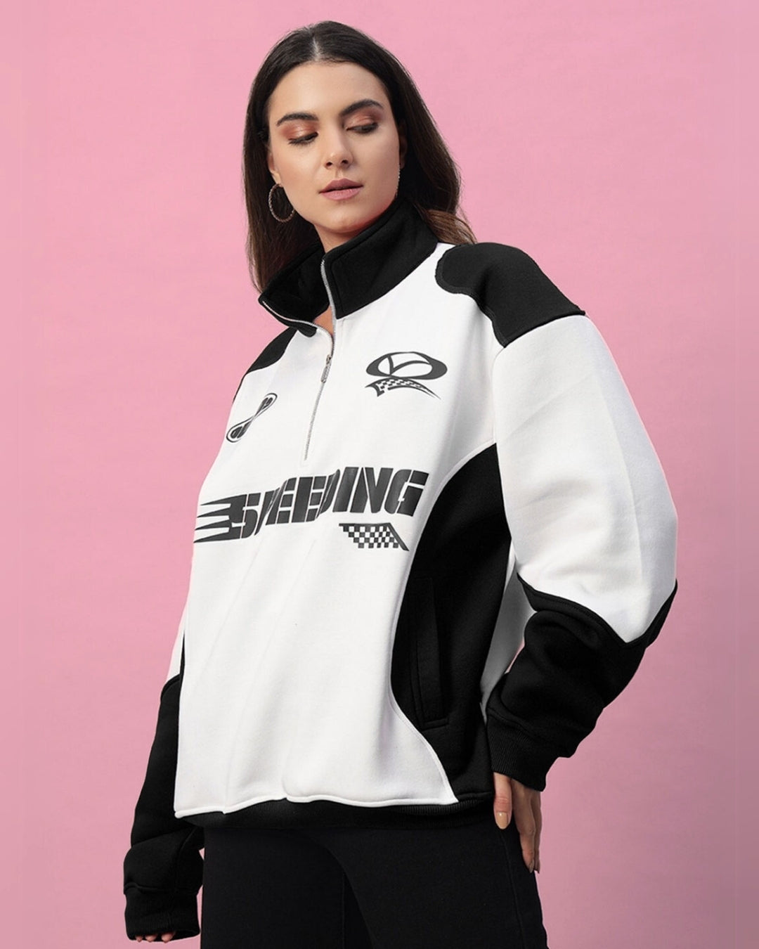 Woman wearing a black and white colorblock jacket featuring bold design elements on a pink background.