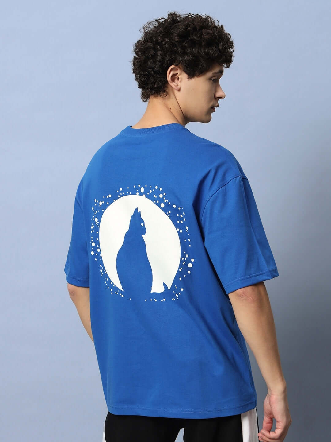 Back view of LUNA OVER-SIZED T-SHIRT ROYAL BLUE with cosmic graphic worn by model.