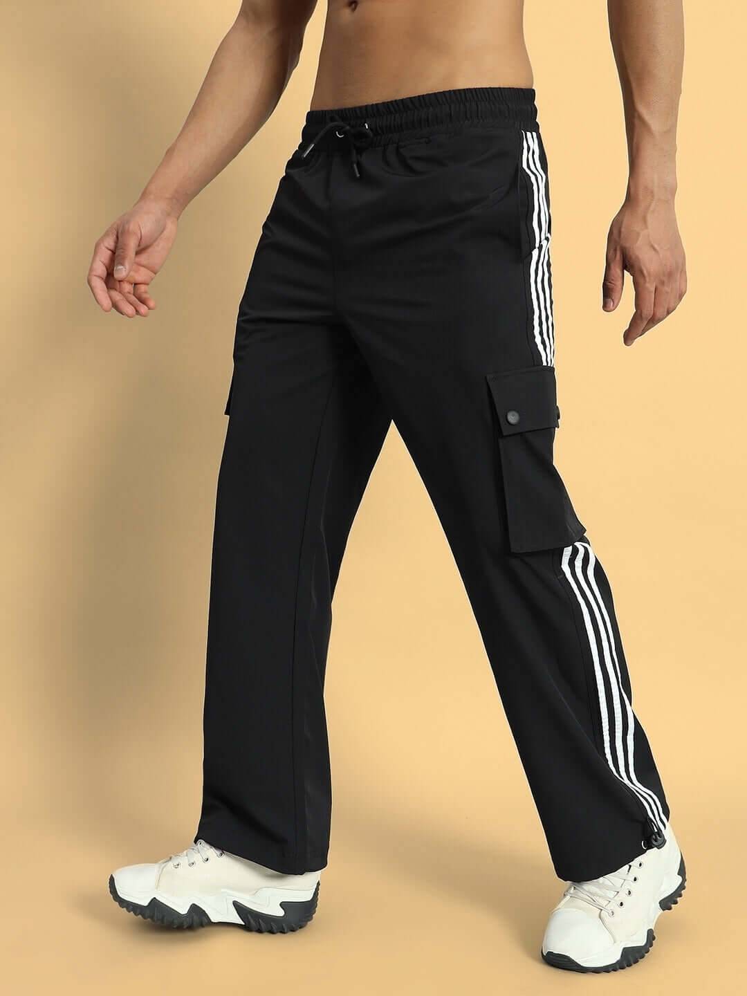 Man wearing Nova Relaxed Fit Cargo Pants in black with side pockets and white stripe detail, paired with white sneakers.