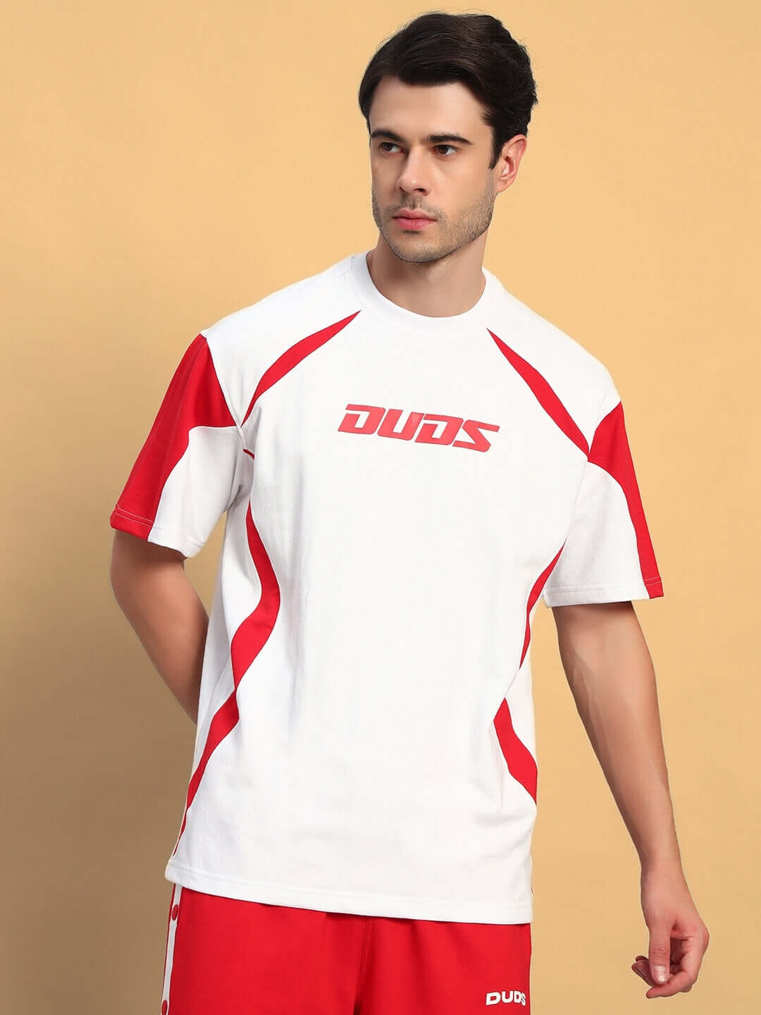 Model wearing Candor oversized white and red t-shirt, made of premium heavy gauge fabric, featuring stylish red accents and logo.