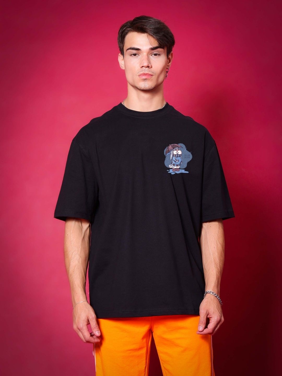 Man wearing BLUE LAPIN OVER-SIZED T-SHIRT BLACK with graphic, premium heavy gauge fabric, on a red background