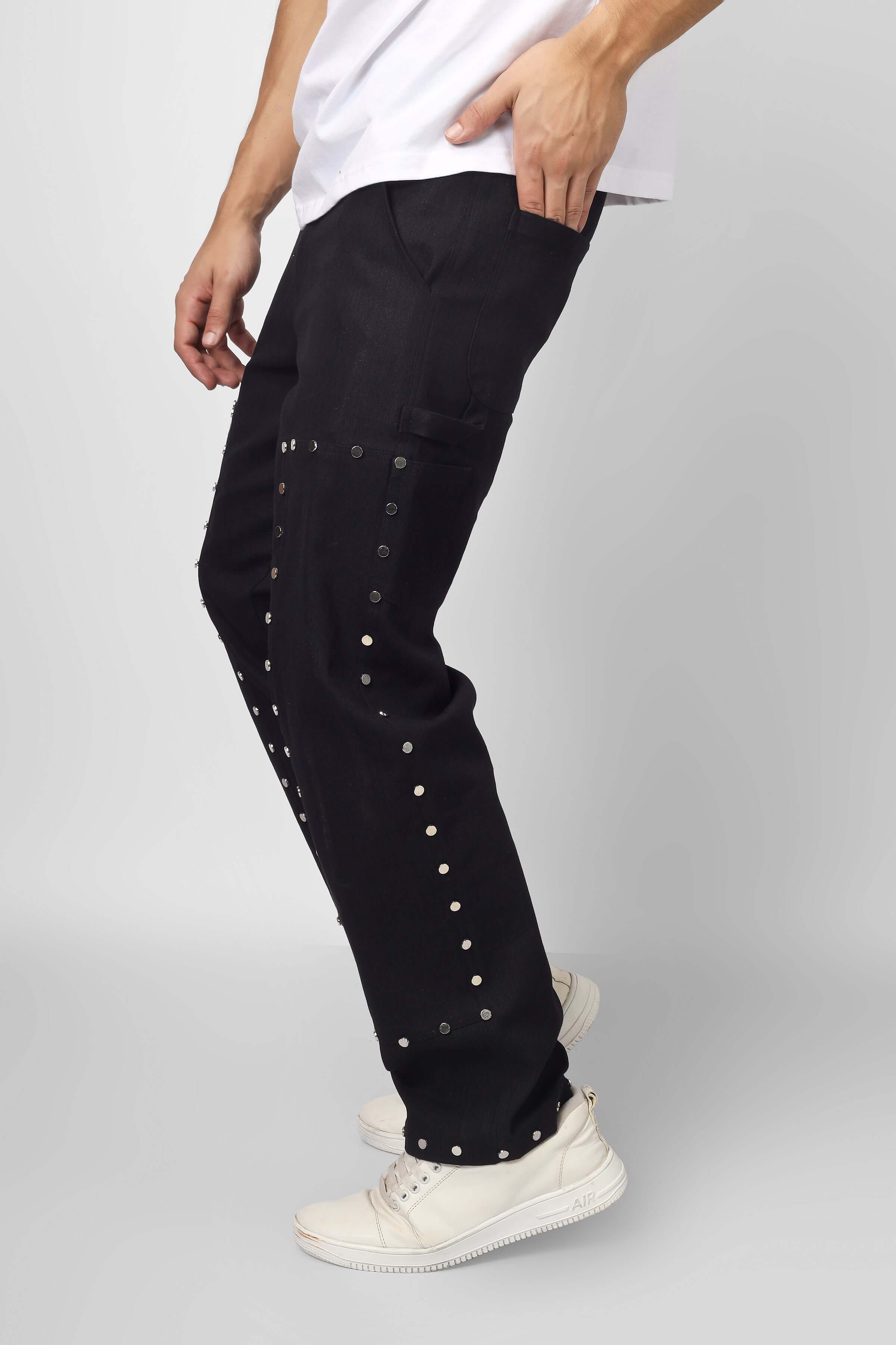 Model wearing black 7 Pocket Multi Metal Stud Button Pants with cotton twill, featuring seven pockets and metal stud detailing.
