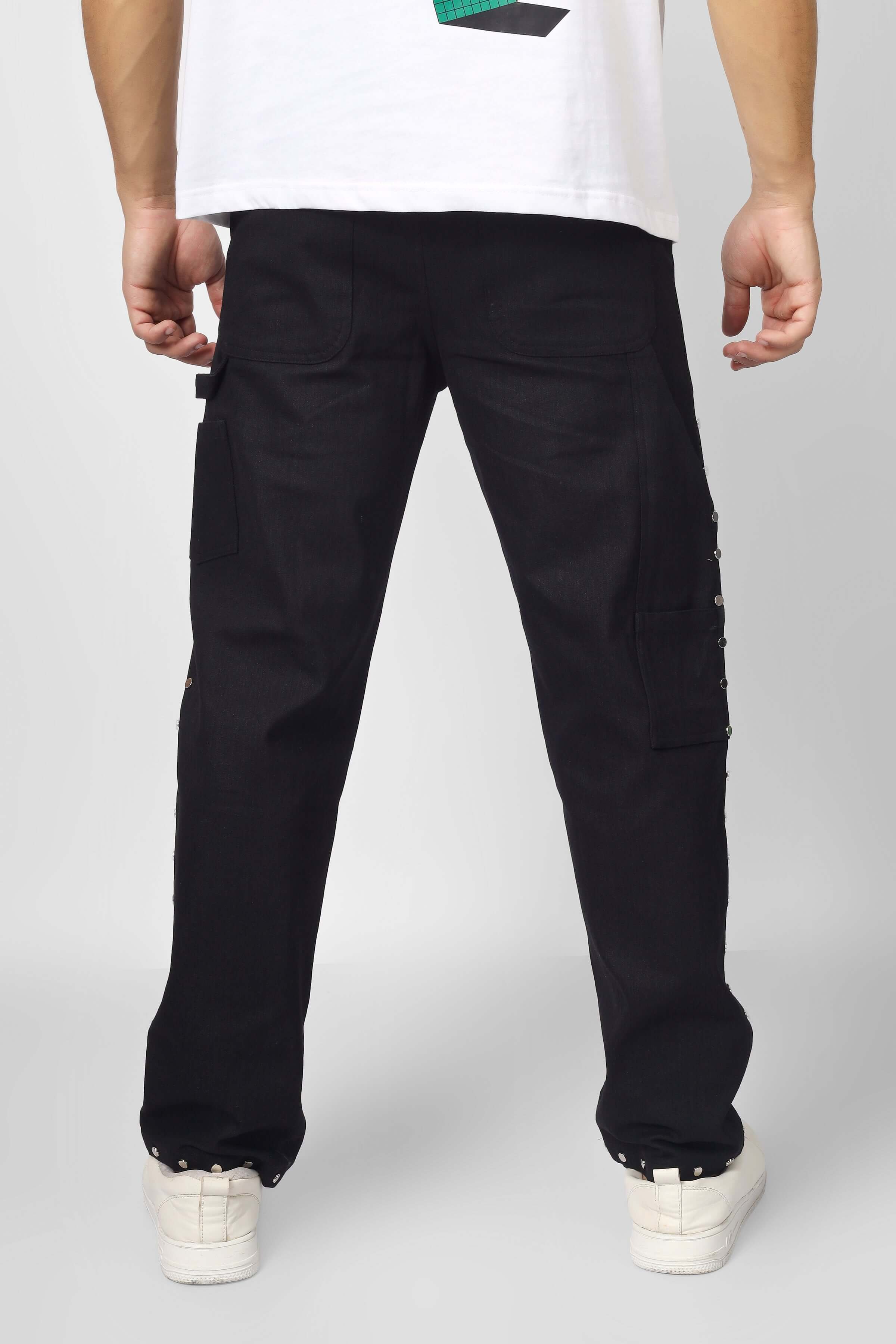 Back view of 7 Pocket Multi Metal Stud Button Pants in black cotton twill, showcasing pocket design and metal stud details.