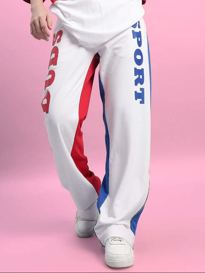 Women's Urban Drift Relaxed Fit Joggers in multi-color, featuring bold text accents, worn with casual white sneakers on a pink background.