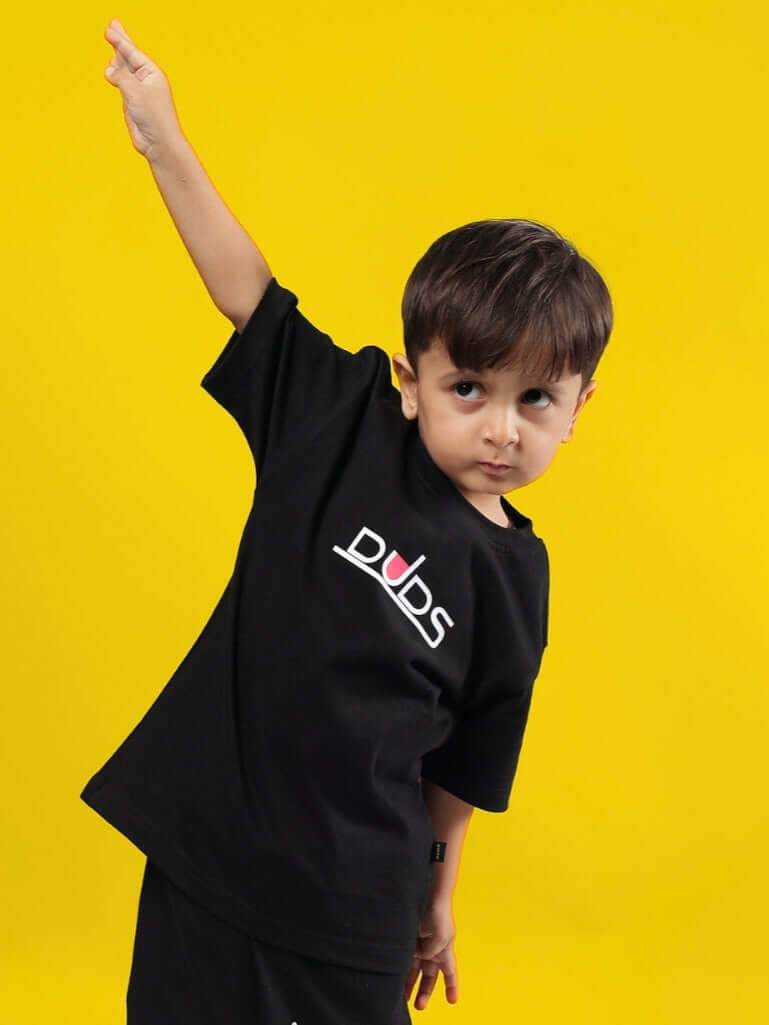 Child wearing black DUDS Squid Battle T-Shirt striking a playful pose against a yellow background.