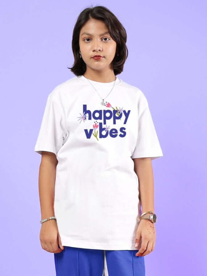 Child wearing white Happy Vibes T-shirt with colorful text, suitable for boys and girls.