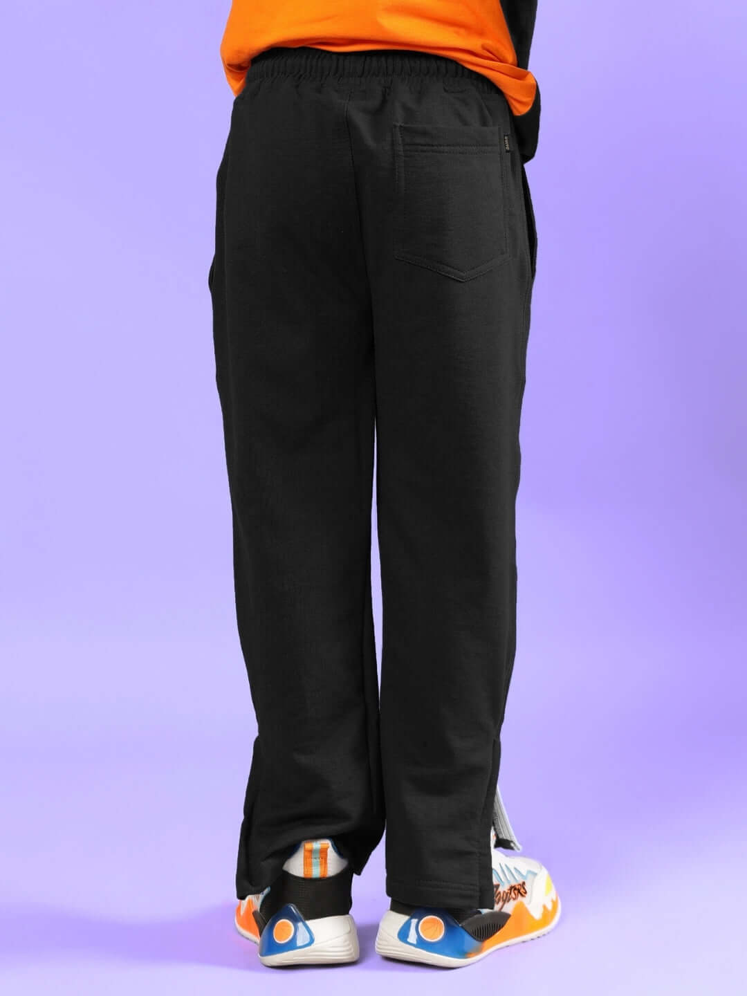 Person wearing multi-black co-ord pants by DUDS, showcasing back view on a purple background.