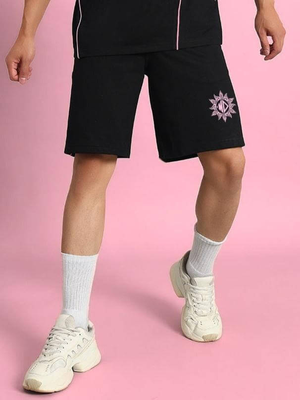Man wearing GLARE regular fit black shorts with sun emblem on left leg, showcasing casual style.