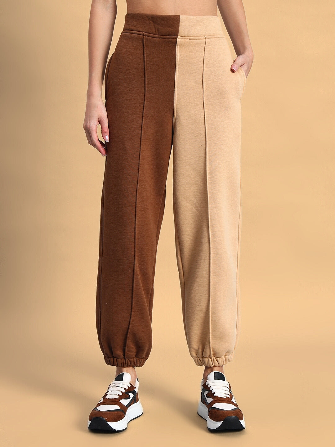 Woman wearing beige-brown Sophia co-ord set, showcasing relaxed fit pants with split color design, paired with stylish sneakers.