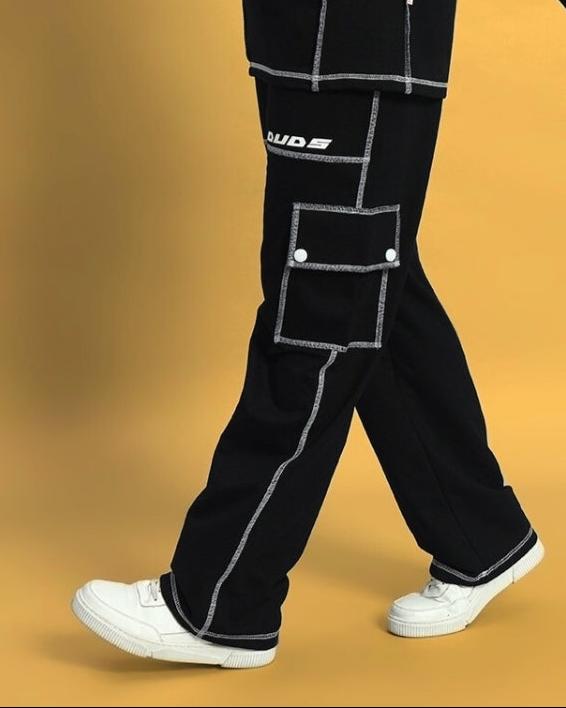 Women's Dynamic 5 Pocket Black Cargo Pant by DUDS, featuring stylish stitching and side pockets, shown in walking motion on yellow background.
