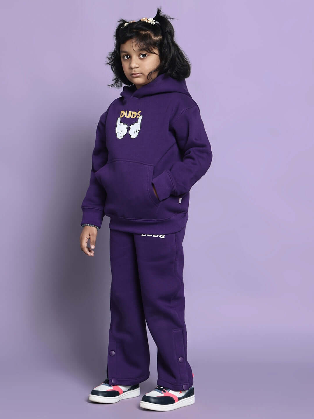 Child wearing a purple Miller co-ord set for boys and girls, featuring a hoodie with playful graphics and comfortable matching pants, against a purple background.