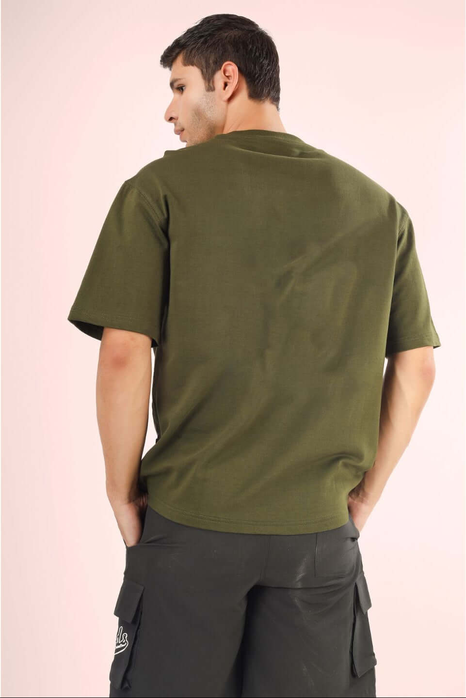 Back view of model wearing FUTURE EXPLORER OVERSIZED T-SHIRT OLIVE GREEN.