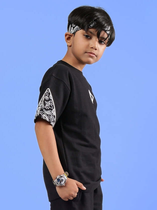 Boy wearing CALVIN oversized black t-shirt with bandana and detailed sleeve design, available for custom fit from DUDS.