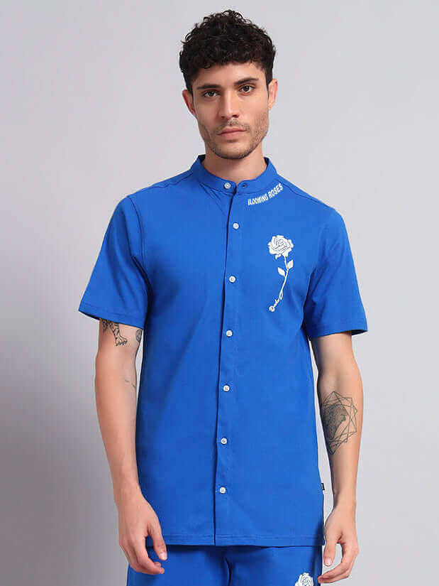 Man wearing a blue LIMBO regular fit shirt, featuring a white floral design and button-down style, made from premium fabric with elastane.