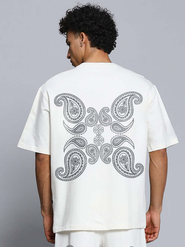 Back view of a man wearing an oversized off-white t-shirt with paisley print, made from premium cotton and elastane blend.