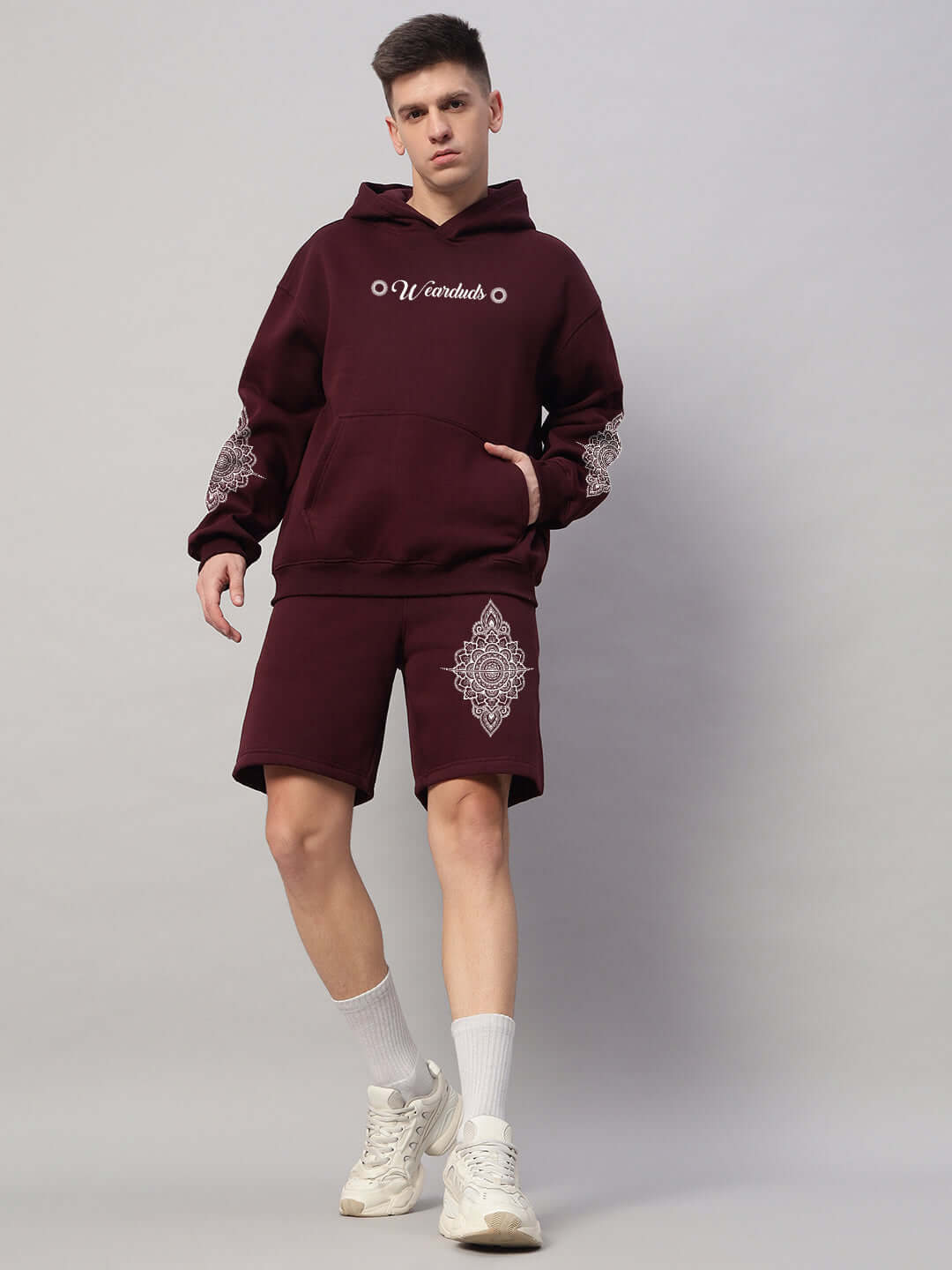 Model wearing Yantra fleece co-ord set for men in wine color with hoodie and shorts, featuring detailed patterns.