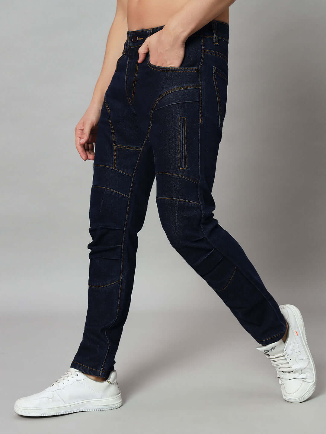 Side view of Novice Contrast Stitch Denim Jeans in blue, featuring unique stitching details, worn with white sneakers.