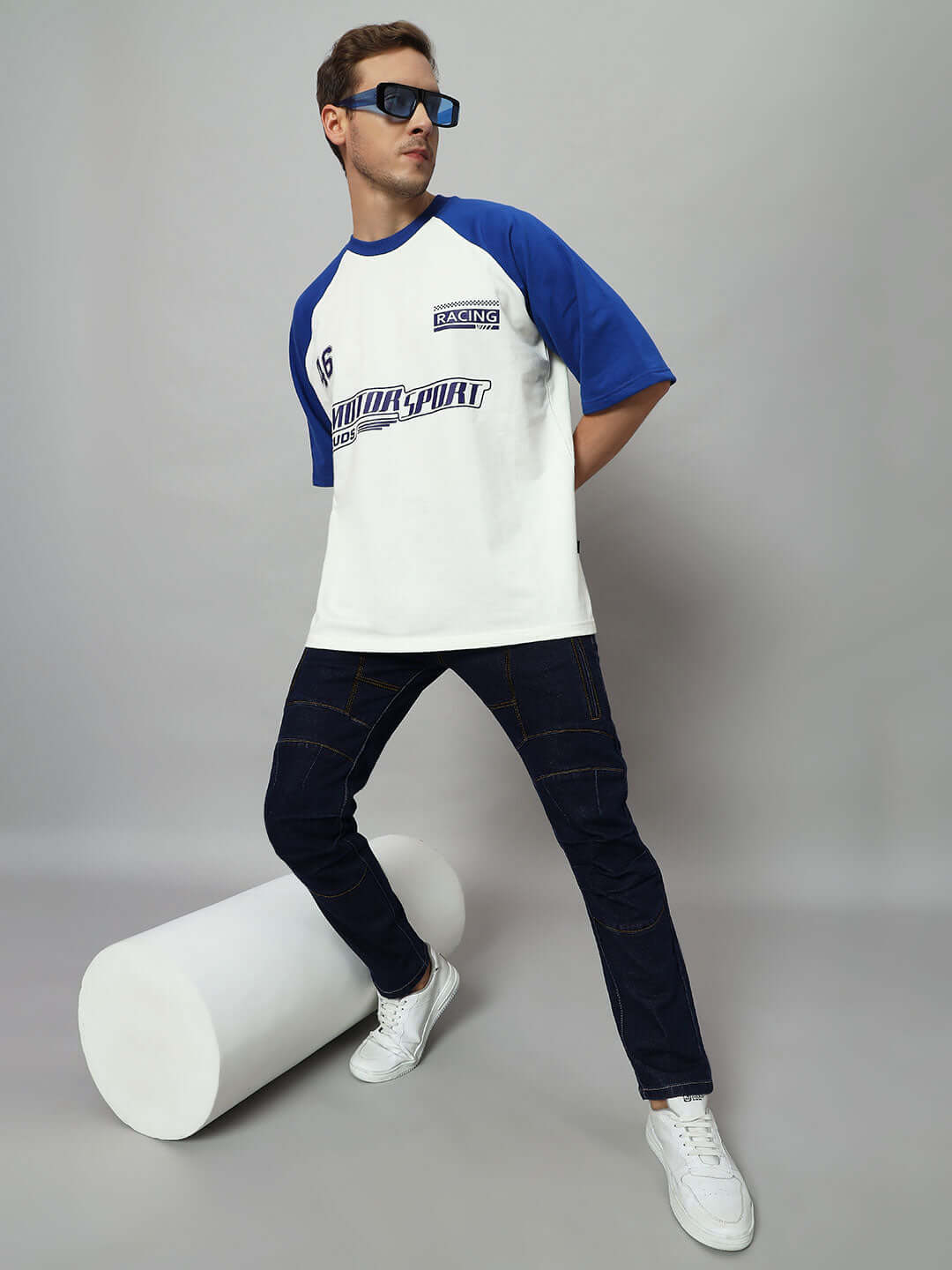 Model wearing NOVICE Contrast Stitch Denim Jeans in blue, paired with a white and blue raglan tee, showcasing a stylish casual look.