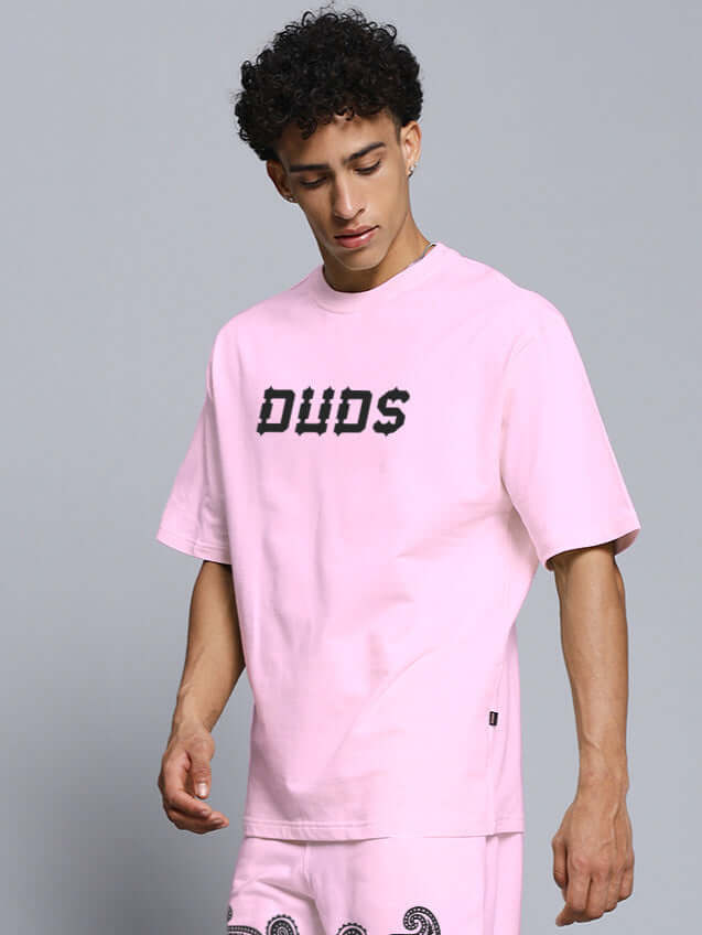 Model wearing pink oversized t-shirt with paisley print. Made from premium cotton blend. Modern casual wear for stylish comfort.