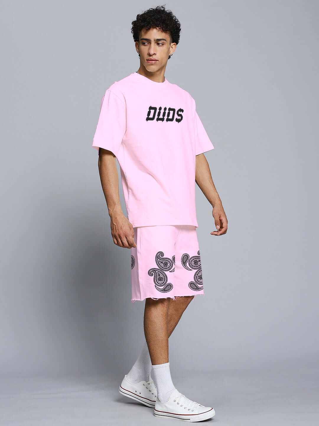 Model wearing Messi Paisley Print Co-ord Set in pink with graphic tee and shorts, made from premium cotton French terry.