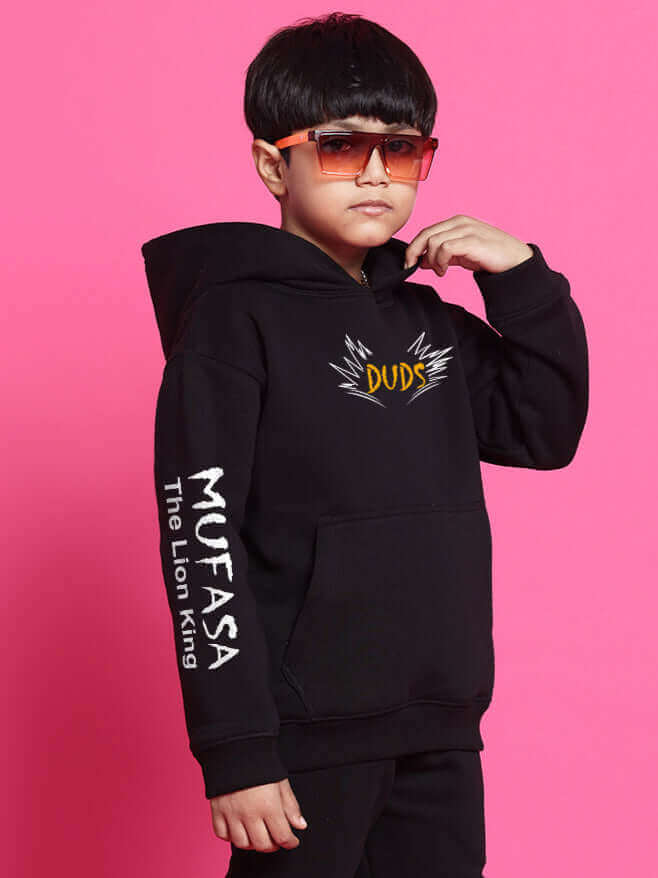 Child wearing MUFASA Fleece Co-ord in black with sunglasses, featuring "DUDS" graphic on the chest and "MUFASA The Lion King" text on sleeve.